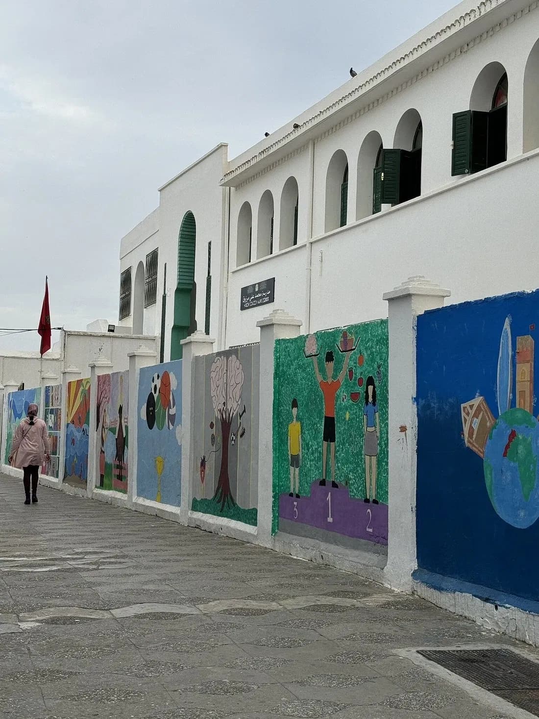 Colourful murals painted on white walls along a street in Asilah