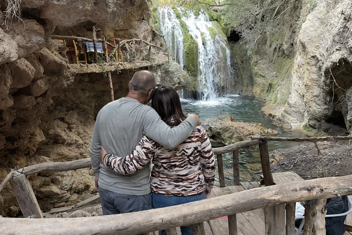 Couple looking at a waterfall from a wooden viewpoint at Akchour