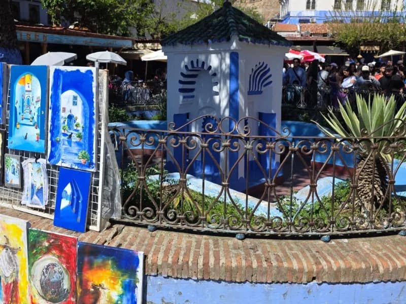 Colourful paintings for sale beside a blue fountain