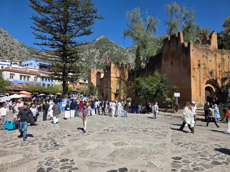 Kasbah walls and a busy square below mountains in Chefchaouen