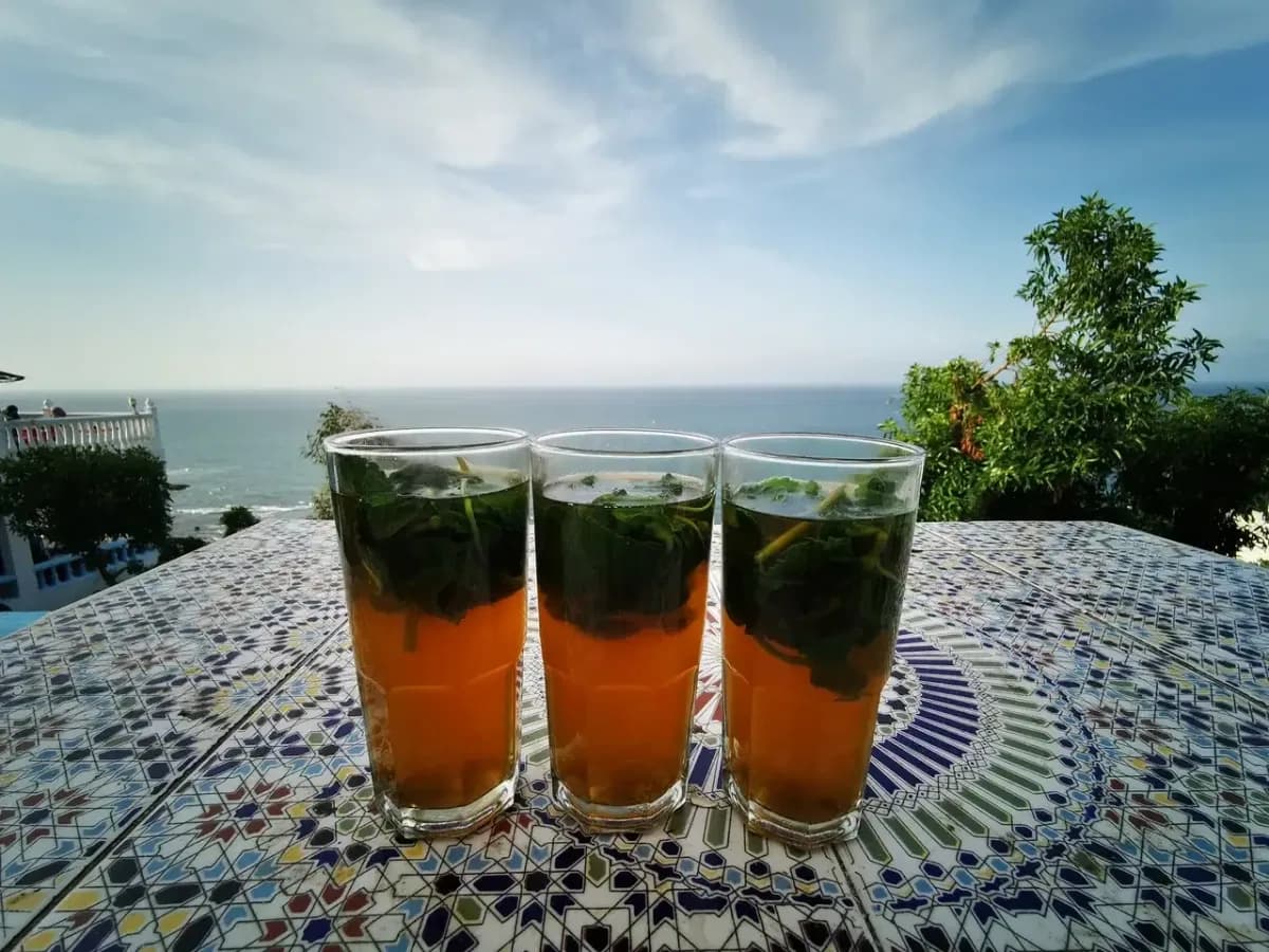 Three glasses of mint tea on a mosaic table overlooking the sea